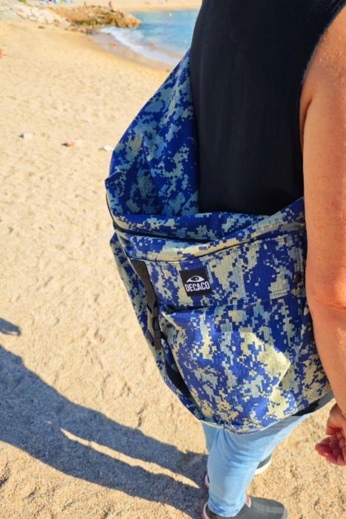 Female model showcasing our blue digital camouflage hobo XXL bag on a sunny beach day. Perfect for a casual, bohemian style.